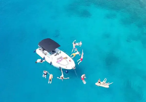 Cap Camarat 7.5 from above — guests swimming around the bow in turquoise Adriatic water.