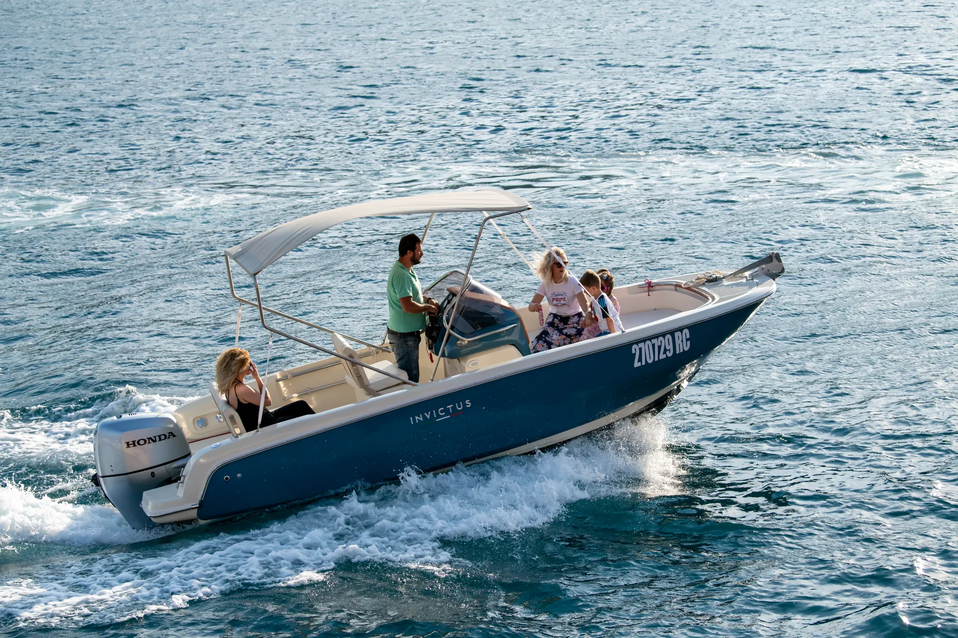 Invictus running at golden hour — family aboard, soft Adriatic light.