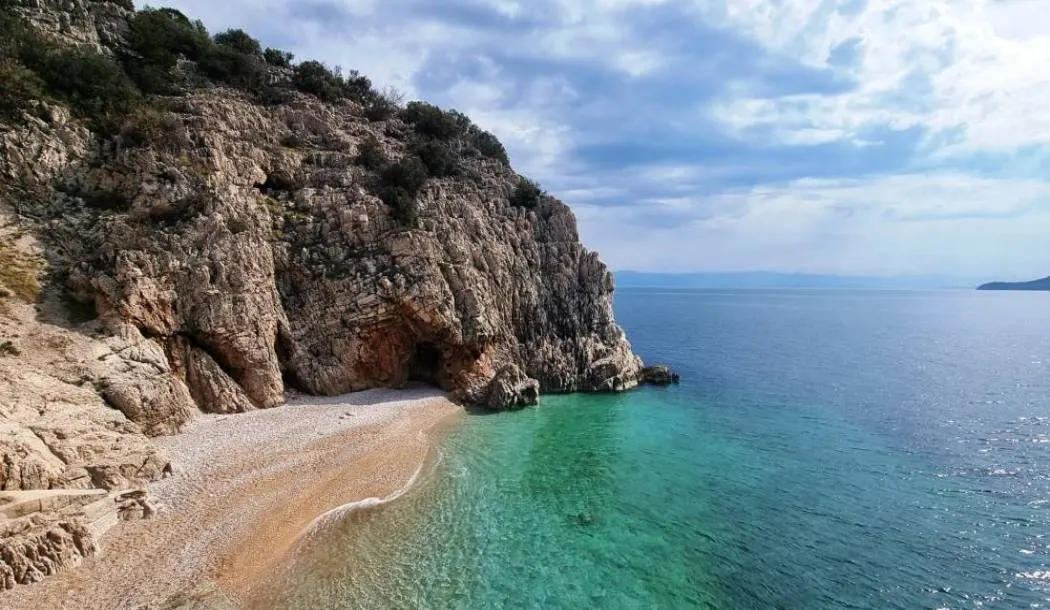 Brseč pebble cove below the cliffs, seen from above.