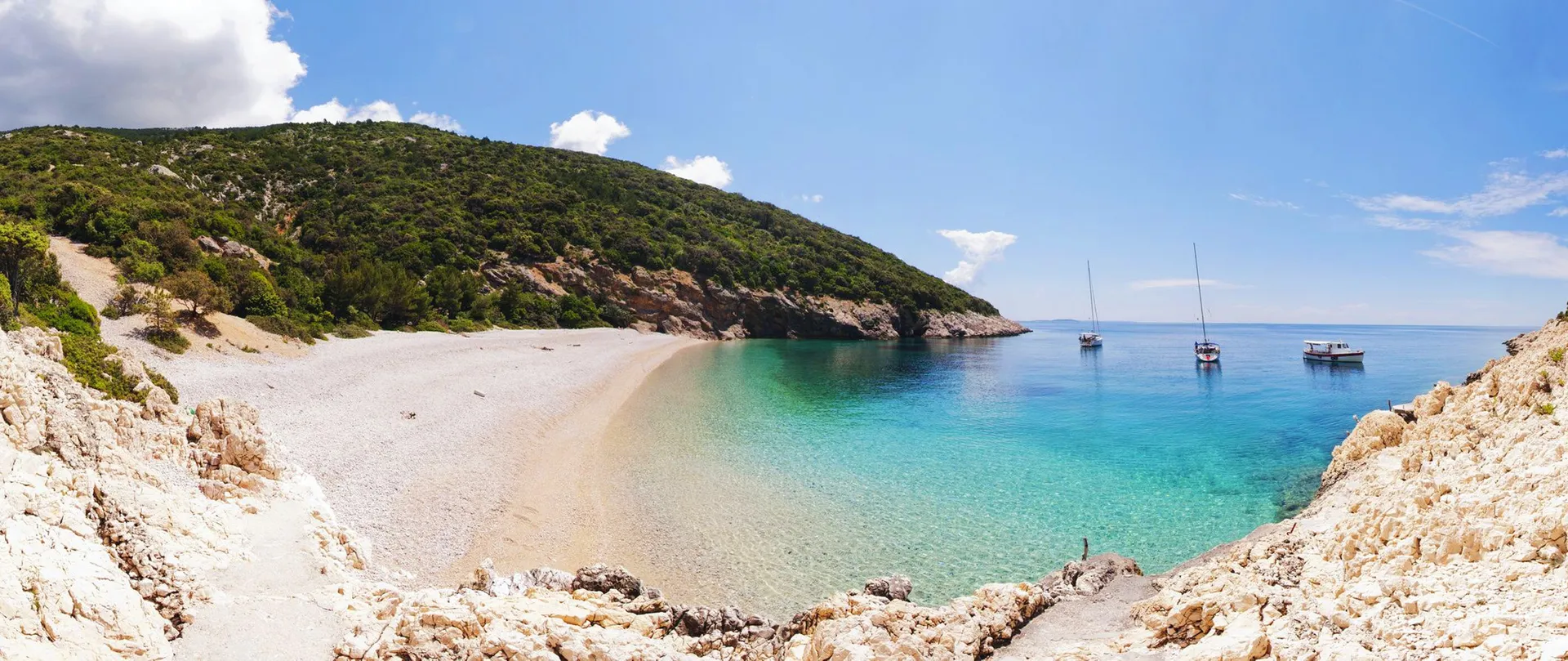 Sveti Ivan beach below the Lubenice cliffs on Cres — fine white pebbles, turquoise water, a small protected bay.